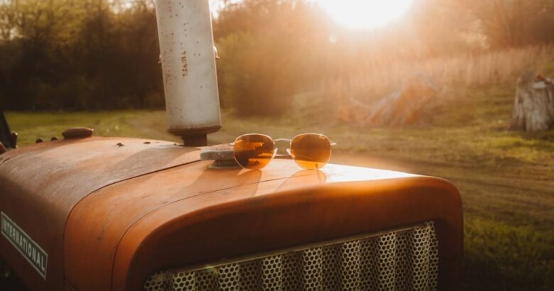 Old orange tractor in field at sunset