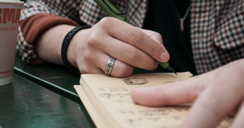 A person sitting at a table writing on a notebook