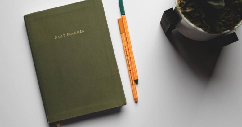 green book beside orange and white pen