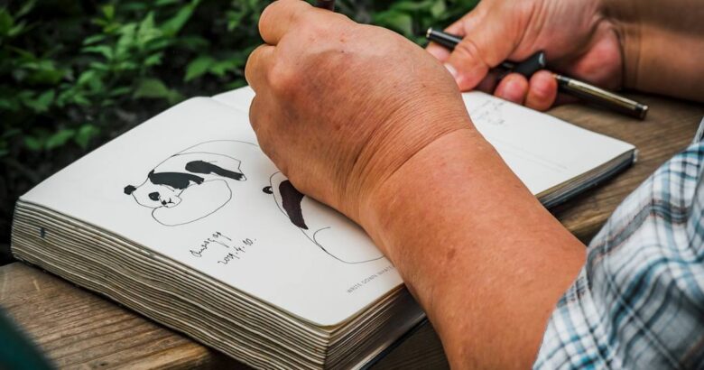 a person writing on a notebook with a pen